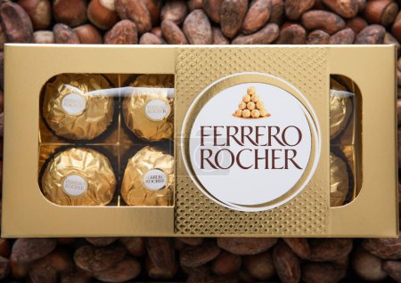 Foto de LONDRES, Reino Unido - 10 de marzo de 2024: Caja de bombones de chocolate Ferrero Rocher sobre fondo de avellana y cacao. - Imagen libre de derechos