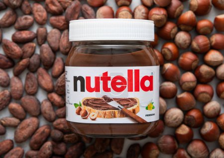 Photo for LONDON, UK - MARCH 02, 2024: Large jar of Nutella chocolate cream on top of hazelnut and cocoa background. - Royalty Free Image