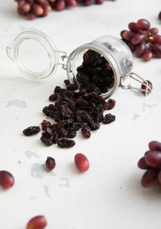 Photo for Dark dried sweet raisins in glass jar on light background.Macro - Royalty Free Image