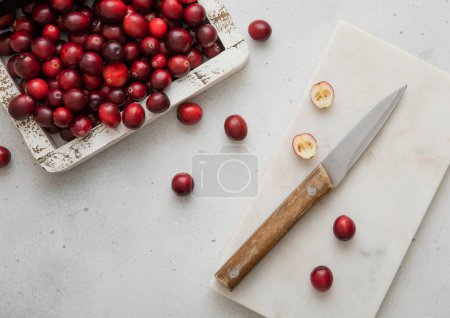 Photo for Wooden box with red ripe cranberries and kitchen knife on light background. - Royalty Free Image