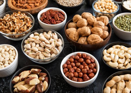 Photo for Mixed raw nuts and seeds in bowls on kitchen table.Peanut,hazelnut,walnut,almonds,pistachio,sunflower,pumpkin,chia and cashew. - Royalty Free Image