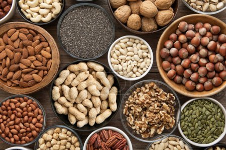 Photo for Peanut,hazelnut,walnut,almonds,pistachio,sunflower,pumpkin,chia,pecan and cashew mixed healthy nuts and seeds in various bowls on wooden background. - Royalty Free Image