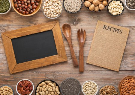 Photo for Peanut,hazelnut,walnut,almonds,pistachio,sunflower,pumpkin,chia,pecan and cashew mixed healthy nuts and seeds with menu and recipe board and kitchen utensils. - Royalty Free Image