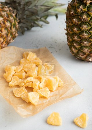 Photo for Yellow organic dried sweet pineapple slices on baking paper on light table.Macro - Royalty Free Image