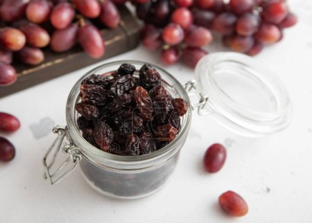 Téléchargez les photos : Raisins secs doux foncés dans un bocal en verre sur fond clair. - en image libre de droit