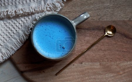 Foto de Latte espirulina azul en taza de cerámica con una cuchara sobre un fondo de tabla de cortar de madera - Imagen libre de derechos
