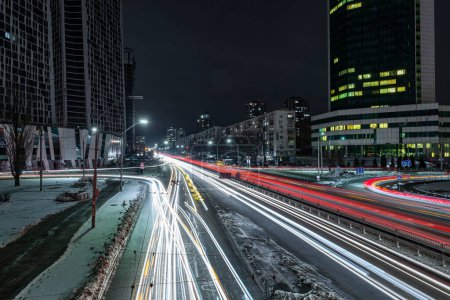 Foto de Tráfico nocturno en la ciudad invernal. Huellas borrosas de faros de coches en la carretera - Imagen libre de derechos