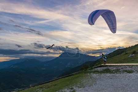 Foto de 2021-08-17 Meduno, Italy. Paraglider pilot at the take-off for a sunset flight - Imagen libre de derechos