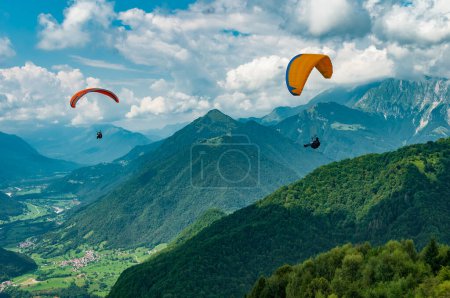 Photo for 08.12.2022 Tolmin, Slovenia. Colorful paraglider wings fly in the mountains near Tolmin, Slovenia. Soca valley, the Europe popular tourist destination, Mecca for extreme sports and active lifestyle. - Royalty Free Image