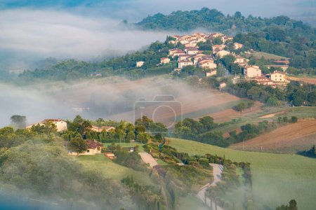 Rolling hills with small towns in the morning fog in Umbria, Italy.