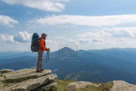 Téléchargez les photos : Femme randonneuse avec sac à dos et bâtons de trekking au sommet de la montagne. Style de vie actif et vacances en plein air dans les montagnes - en image libre de droit