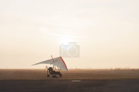 Photo for Motorized hang glider trike on the runway in the early morning. Moody aviation photo - Royalty Free Image