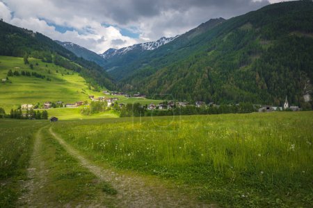 Téléchargez les photos : Campagne alpine pittoresque en Autriche. Pâturage alpin vert et petit village avec des sommets de haute montagne sur le fond. paysage autrichien emblématique - en image libre de droit