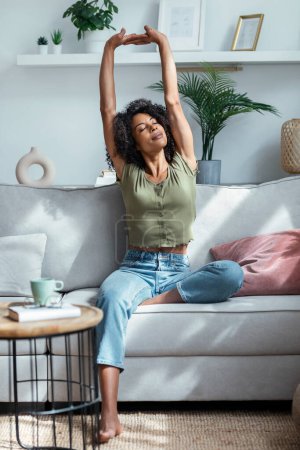 Photo for Shot of beautiful woman stretching while relaxing on the coach at home. - Royalty Free Image