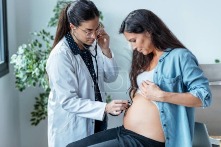 Téléchargez les photos : Prise de vue d'une gynécologue vérifiant le pouls du bébé de sa patiente enceinte à la clinique. - en image libre de droit