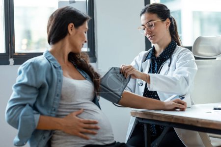 Téléchargez les photos : Prise de vue d'une gynécologue féminine vérifiant la pression artérielle de sa patiente enceinte à la clinique. - en image libre de droit