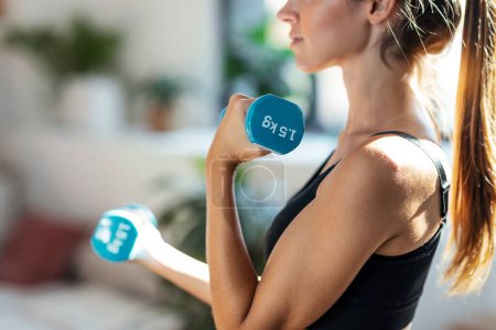Photo for Shot of sporty young woman lifting dumbbells at home - Royalty Free Image