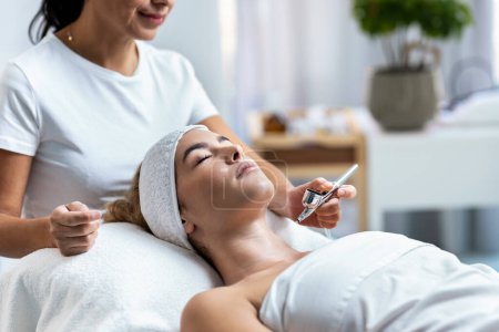Téléchargez les photos : Shot of beautiful woman getting oxygen face therapy in a beauty salon. Professional skin care treatment. - en image libre de droit