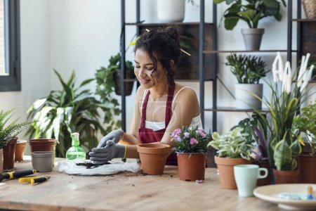 Foto de Fotografía de una mujer influencer arreglando plantas y flores mientras graba un video tutorial con smartphone en un invernadero - Imagen libre de derechos