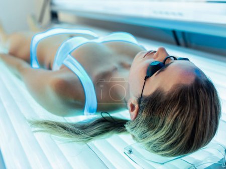 Téléchargez les photos : Prise de vue de belle femme ayant bronzage traitement de la peau dans un solarium - en image libre de droit