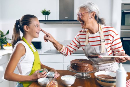 Photo for Shot of happy family grandmother and granddaughter making chocolate cake in the kitchen - Royalty Free Image