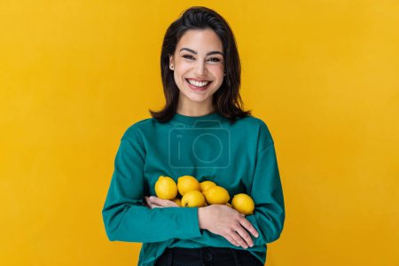 Téléchargez les photos : Portrait d'une femme riante tenant des citrons isolés sur jaune - en image libre de droit