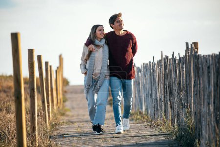 Foto de Retrato de una hermosa pareja joven enamorada caminando juntos en un frío día de invierno en la playa. - Imagen libre de derechos