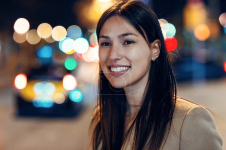 Photo for Portrait of attractive smiling young woman walking in the street at night. - Royalty Free Image