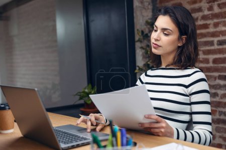 Photo for Shot of architect engineer woman working with laptop while studying the blueprints in a modern office. - Royalty Free Image