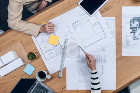 Photo for Close up of  hands of architects working with blueprints of their new design business in the office. - Royalty Free Image