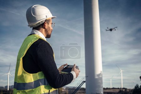 Photo for Video of mature man engineers flying a drone over the wind generator field while checking that everything is correct - Royalty Free Image