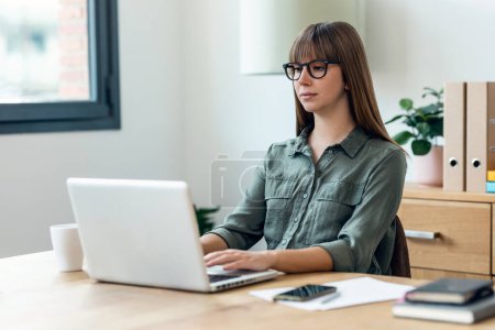 Téléchargez les photos : Tourné de concentré jeune belle femme d'affaires travaillant avec ordinateur portable dans le bureau. - en image libre de droit