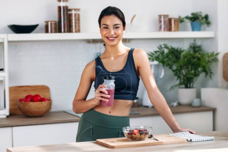Shot of athletic woman drinking healthy protein shake in the kitchen at home