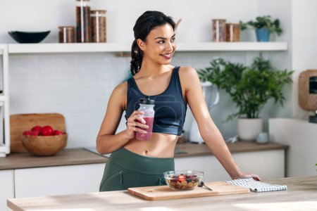 Photo for Shot of athletic woman drinking healthy protein shake in the kitchen at home - Royalty Free Image