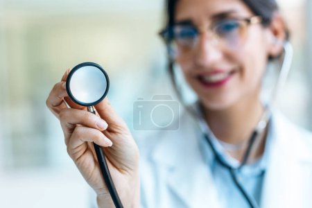Photo for Shot of smiling female doctor holding a stethoscope while looking at camera in the medical consultation. - Royalty Free Image