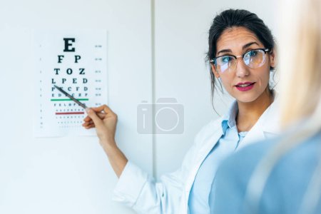 Photo for Shot of beautiful female optician doing eye test with eye chart on her patient in ophthalmology clinic - Royalty Free Image