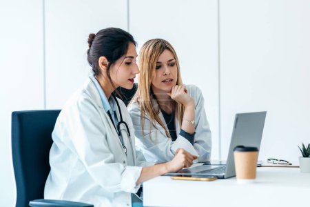 Photo for Shot of two beautiful female doctors working with her laptop while talking in the medical consultation - Royalty Free Image