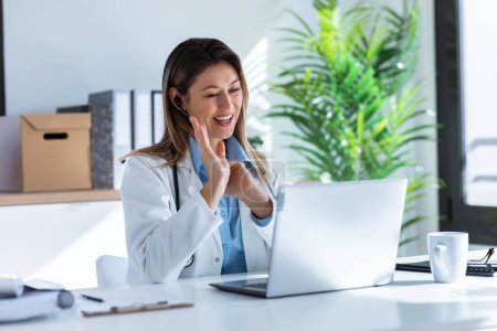 Photo for Shot of female doctor talking with colleagues through a video call with a laptop in the consultation. - Royalty Free Image