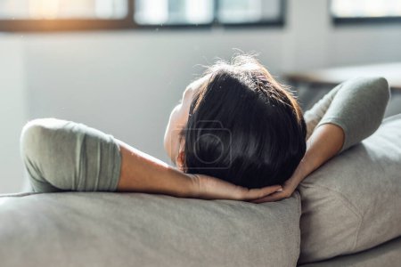 Foto de Tiro de mujer cansada joven relajándose mientras está tumbado en el sofá en la sala de estar en casa. - Imagen libre de derechos