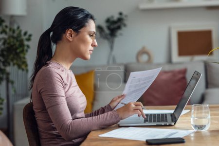 Téléchargez les photos : Prise de vue de belle jeune femme regardant des papiers tout en travaillant avec PC - en image libre de droit