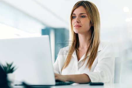 Téléchargez les photos : Prise de vue d'une élégante femme d'affaires attrayante travaillant avec un ordinateur portable dans une start-up moderne - en image libre de droit