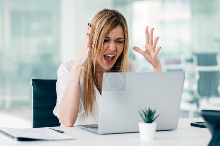 Foto de Tiro de mujer de negocios enojada preocupada que trabaja con el ordenador portátil mientras tiene problemas en una startup moderna - Imagen libre de derechos