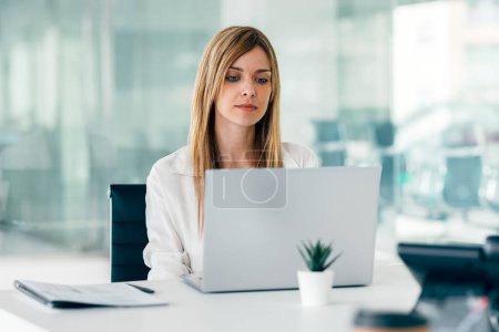 Foto de Tiro de mujer de negocios atractiva elegante que trabaja con el ordenador portátil en una startup moderna - Imagen libre de derechos