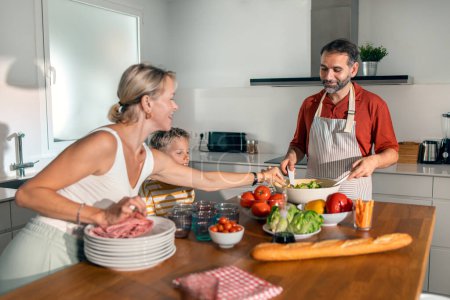Foto de Tiro de hermosa clase familia cocina ensalada saludable juntos en la cocina en casa - Imagen libre de derechos