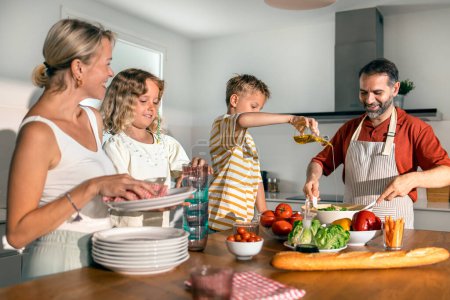 Foto de Tiro de hermosa clase familia cocina ensalada saludable juntos en la cocina en casa - Imagen libre de derechos