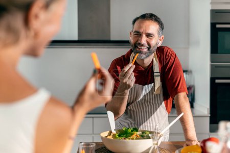 Téléchargez les photos : Tourné de belle cuisine familiale aimable salade saine ensemble dans la cuisine à la maison - en image libre de droit