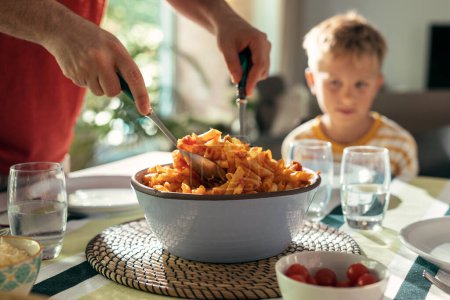 Téléchargez les photos : Tourné de belle famille aimable parler tout en mangeant ensemble dans la cuisine à la maison - en image libre de droit