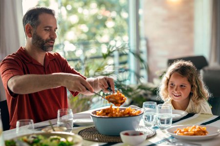 Téléchargez les photos : Tourné de belle famille aimable parler tout en mangeant ensemble dans la cuisine à la maison - en image libre de droit