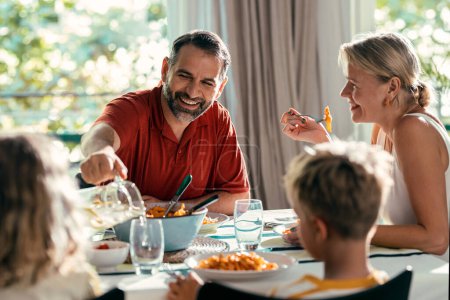 Tourné de belle famille aimable parler tout en mangeant ensemble dans la cuisine à la maison