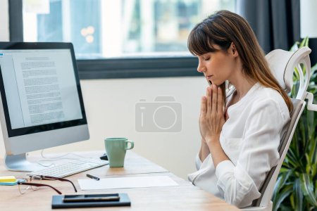 Foto de Foto de hermosa mujer nutricionista inteligente haciendo meditación mientras trabaja con la computadora en una consulta nutricionista - Imagen libre de derechos